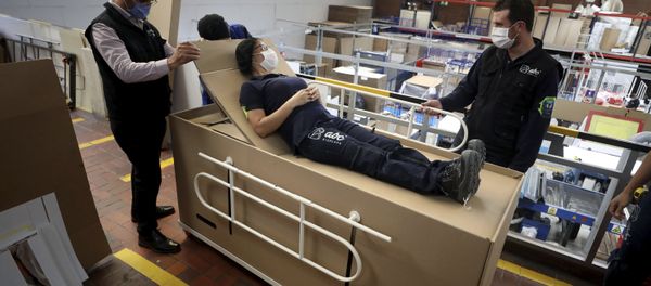 Rodolfo Gomez, left, and his employees demonstrate how their design of a cardboard box can serve as both a hospital bed and a coffin - Sputnik International