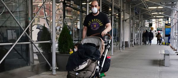A man wearing a protective mask pushes a child wearing a protective mask in a stroller during the coronavirus pandemic on April 12, 2020 in New York City. - Sputnik International