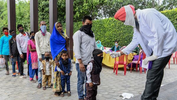 A health worker checks the body temperature of migrant workers before they go to Amritsar railway station to take a special train to Ambedkar Nagar in Uttar Pradesh state back to their hometowns after the government eased a nationwide lockdown imposed as a preventive measure against the COVID-19 coronavirus,on the outskirts of  Amritsar on May 13, 2020 - Sputnik International
