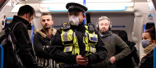 A police officer wearing PPE (personal protective equipment), including a face mask as a precautionary measure against COVID-19, stands with commuters as they travel in the morning rush hour on TfL (Transport for London) London underground Victoria Line trains from Finsbury Park towards central London on May 13, 2020 A police officer wearing PPE (personal protective equipment), including a face mask as a precautionary measure against COVID-19, stands with commuters as they travel in the morning rush hour on TfL (Transport for London) London underground Victoria Line trains from Finsbury Park towards central London on May 13, 2020 - Sputnik International