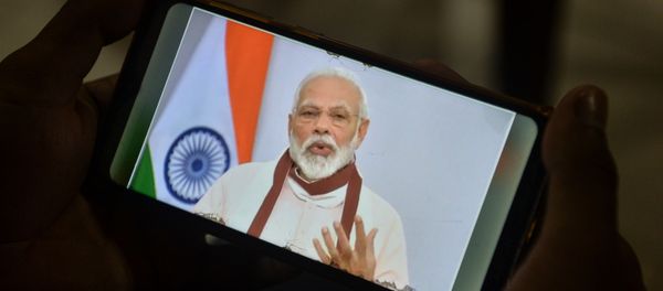 A youth watches Indian Prime Minister Narendra Modi's address to the nation on his mobile phone during a government-imposed nationwide lockdown as a preventive measure against the COVID-19 coronavirus, in Siliguri on 12 May 2020.  - Sputnik International