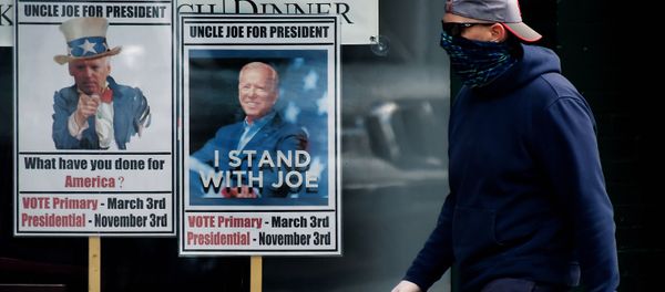 A man wearing a face mask walks past signs for Joe Biden's 2020 presidential campaign amid the coronavirus outbreak on May 11, 2020 in Alexandria, Virginia - Sputnik International