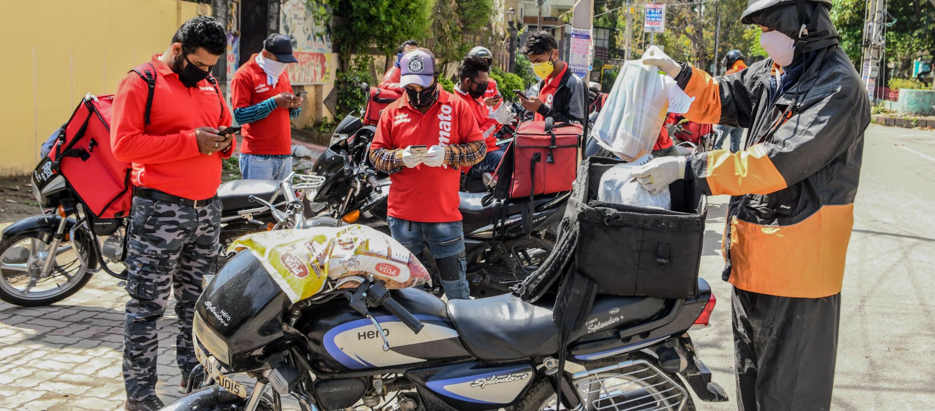 A Swiggy delivery man (R) wearing a facemask puts food commodities in the bag tied to his motorbike to deliver to customers as other Zomato delivery men check their mobile phones during a government-imposed nationwide lockdown as a preventive measure against the COVID-19 coronavirus, in Amritsar on March 28, 2020 A Swiggy delivery man (R) wearing a facemask puts food commodities in the bag tied to his motorbike to deliver to customers as other Zomato delivery men check their mobile phones during a government-imposed nationwide lockdown as a preventive measure against the COVID-19 coronavirus, in Amritsar on March 28, 2020 - Sputnik International, 1920, 21.05.2020