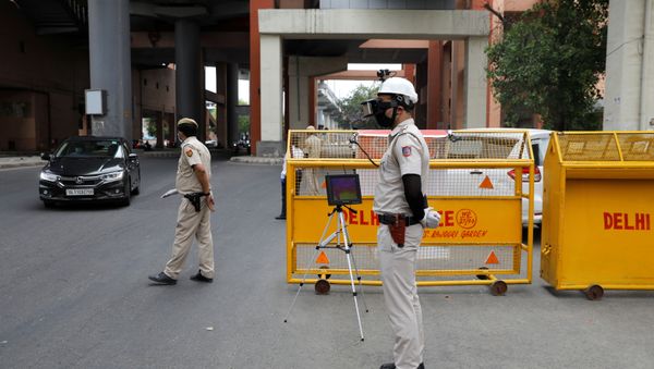 A police officer wears a Thermal Corona Combat Headgear to monitor the temperature of commuters at a police check post, during a nationwide lockdown to slow the spread of the coronavirus disease (COVID-19), in New Delhi, India May 11, 2020.  - Sputnik International