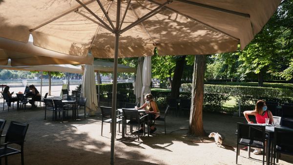 People wearing face masks sit at an outdoor seating section of a kiosk at Retiro Park as it is reopened for the first time in more than 2 months amid the coronavirus disease (COVID-19) outbreak, in Madrid, Spain May 25, 2020 - Sputnik International