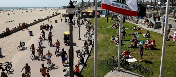 People sit at the beach as cyclists ride bicycles on Memorial Day weekend during the outbreak of the coronavirus disease (COVID-19) in Huntington Beach, California, U.S., May 23, 2020. People sit at the beach as cyclists ride bicycles on Memorial Day weekend during the outbreak of the coronavirus disease (COVID-19) in Huntington Beach, California, U.S., May 23, 2020. - Sputnik International