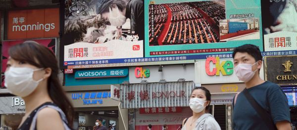 People walk past a TV screen showing the closing session of the National People's Congress (NPC) in Beijing where voting on the national security legislation for Hong Kong took place, in Hong Kong, China May 28, 2020. - Sputnik International