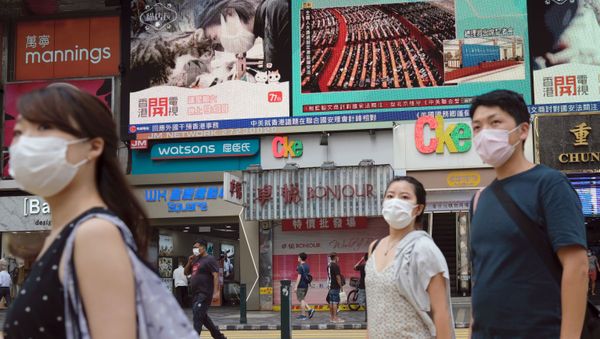 People walk past a TV screen showing the closing session of the National People's Congress (NPC) in Beijing where voting on the national security legislation for Hong Kong took place, in Hong Kong, China May 28, 2020. - Sputnik International