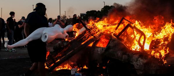 A man prepares to throw a mannequin onto a burning car at the parking lot of a Target store during protests after a white police officer was caught on a bystander's video pressing his knee into the neck of African-American man George Floyd, who later died at a hospital, in Minneapolis, Minnesota, U.S., May 28, 2020 - Sputnik International