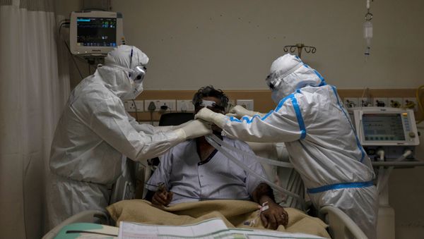 Medical workers wearing PPE take care of a patient suffering from COVID-19, at a hospital in New Delhi - Sputnik International