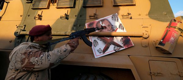 A member of Libyan National Army (LNA) commanded by Khalifa Haftar, points his gun to the image of Turkish President Tayyip Erdogan hanged on a Turkish military armored vehicle, which LNA said they confiscated during Tripoli clashes, in Benghazi, Libya January 28, 2020 - Sputnik International