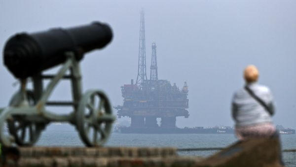 A member of the public stands on the shoreline looking out to sea, as Shell's Brent Delta Topside offshore oil drilling rig platform is towed by tug boats off the coast of Hartlepool, north-east England, on May 2, 2017 - Sputnik International