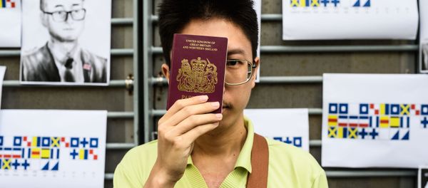 An activist holds a British passport while standing in front of placards carrying a message using International Code of Signals (ICS) flags, during a gathering outside the British Consulate-General building in Hong Kong on August 21, 2019 - Sputnik International