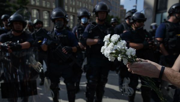 A demonstrator holds flowers as to place at the feet of a line of military near the White House to protest the death of George Floyd, Wednesday, June 3, 2020, in Washington - Sputnik International