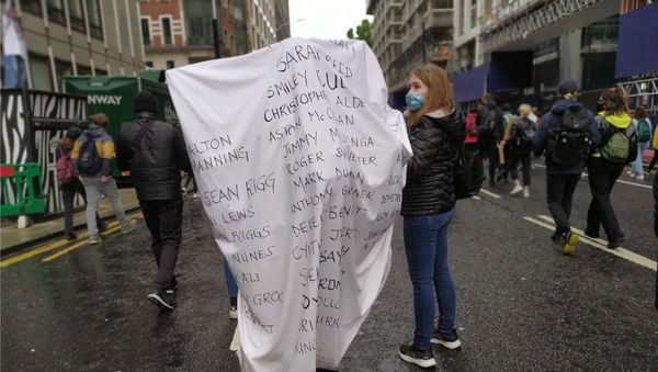 A woman walks down Victoria Street with the names of some of the people who have died in police custody in the UK over the last 10 years written on a sheet on her back. A woman walks down Victoria Street with the names of some of the people who have died in police custody in the UK over the last 10 years written on a sheet on her back. - Sputnik International