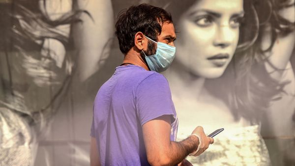 A man uses his mobile phone as he queues to buy alcohol outside a liquor shop after the government eased a nationwide lockdown imposed as a preventive measure against the COVID-19 coronavirus in Gurgaon on May 6, 2020 - Sputnik International