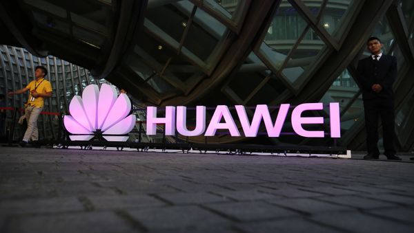 People walk past an illuminated logo for Huawei at a launch event for the Huawei MateBook in Beijing, Thursday, May 26, 2016 - Sputnik International