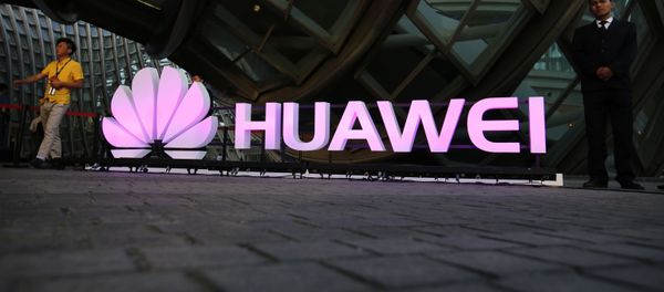 People walk past an illuminated logo for Huawei at a launch event for the Huawei MateBook in Beijing, Thursday, May 26, 2016 - Sputnik International