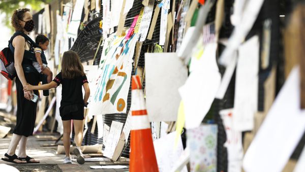 Cristy Hickson of Baltimore, with her children Jaylan Ott, 7, and Jayden Everly, 8 months, look at signs hanging on a police fence at 16th and H Street, Tuesday, June 9, 2020, near the White House in Washington, after days of protests over the death of George Floyd, a black man who was in police custody in Minneapolis. Floyd died after being restrained by Minneapolis police officers.(AP Photo/Jacquelyn Martin) - Sputnik International