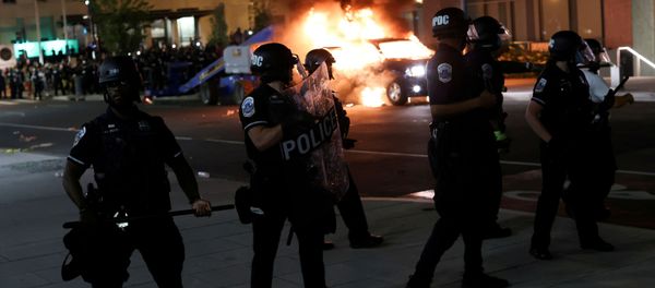Police officers look on as a car burns in the back as protesters continue to rally against the death in Minneapolis police custody of George Floyd, near the White House, in Washington, U.S., May 30, 2020. - Sputnik International