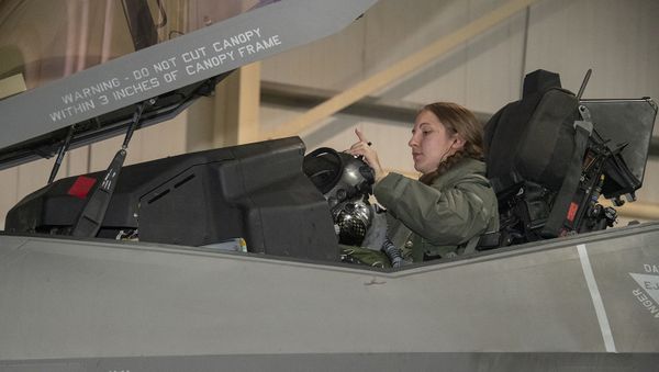 U.S. Air Force Capt. Emily Thompson, 421st Expeditionary Fighter Squadron pilot, dons her helmet prior to a mission on the Al Dhafra Air Base, United Arab Emirates, flightline June 5, 2020. Thompson is the first female to fly an F-35A Lightning II into combat. She is currently deployed from Hill Air Force Base, Utah - Sputnik International