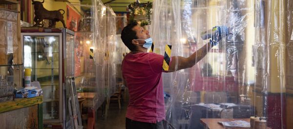 Cafe owner Francini Osorio sprays air sanitiser where he has installed an air purifier and 35 clear shower curtains Cafe owner Francini Osorio sprays air sanitiser where he has installed an air purifier and 35 clear shower curtains - Sputnik International