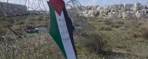 Placard with the colors of the Palestinian flags in front of Israeli barrier. - Sputnik International