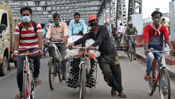 People wearing protective face masks ride their bicycles on Howrah bridge, after authorities eased lockdown restrictions that were imposed to slow the spread of the coronavirus disease (COVID-19), in Kolkata, India, June 12, 2020 - Sputnik International