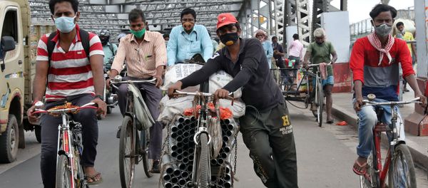People wearing protective face masks ride their bicycles on Howrah bridge, after authorities eased lockdown restrictions that were imposed to slow the spread of the coronavirus disease (COVID-19), in Kolkata, India, June 12, 2020 - Sputnik International