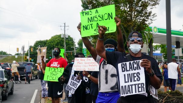 In this file photo taken on June 14, 2020 People hold signs toward traffic outside a burned Wendy’s restaurant on the second day following the police shooting death of Rayshard Brooks in the restaurant parking lot, in Atlanta, Georgia. - Sputnik International