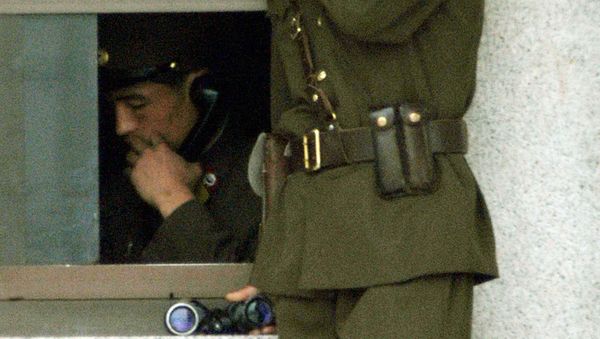 A North Korean border guard looks over across the border to south while the other soldier communicates on a phone in an observation post at Panmunjom, 60 kilometers, 37 miles north of Seoul, Wednesday, July, 2, 2003 - Sputnik International