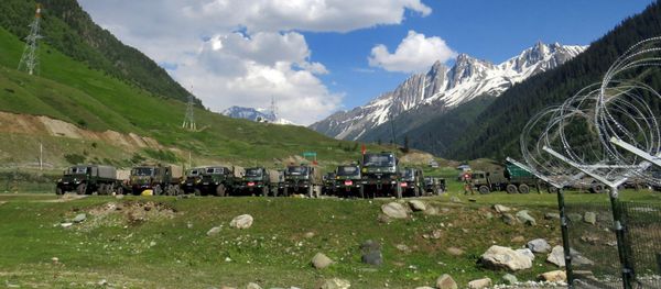 Indian army soldiers walk past their parked trucks at a makeshift transit camp before heading to Ladakh, near Baltal, southeast of Srinagar, June 16, 2020. - Sputnik International