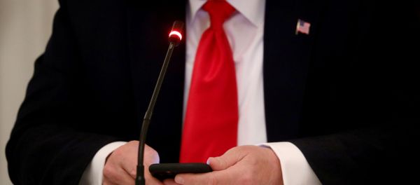 U.S. President Donald Trump is seen tapping the screen on a mobile phone during a roundtable discussion on the reopening of small businesses in the State Dining Room at the White House in Washington, U.S., June 18, 2020 - Sputnik International