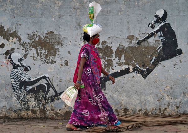 A woman wearing a protective face mask walks past graffiti after authorities eased lockdown restrictions that were imposed to slow the spread of the coronavirus disease (COVID-19) in Mumbai, India, 12 June 2020. - Sputnik International