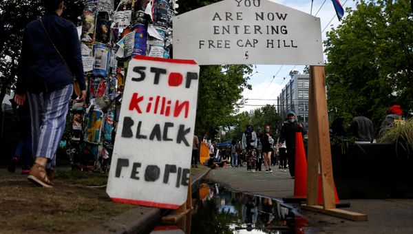 People walk by signs at a barrier set up at the edge of the self-proclaimed CHAZ/CHOP zone around the Seattle Police Department's East Precinct as people call for the defunding of police and protest against racial inequality in the aftermath of the death in Minneapolis police custody of George Floyd, in Seattle, Washington, U.S. June 14, 2020 - Sputnik International