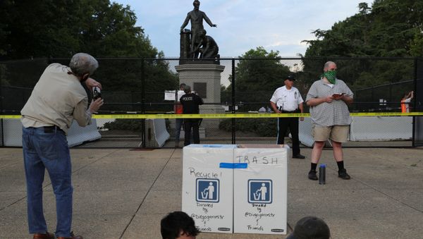 A park attendee takes a cell phone photo while another reads a book outside of an enclosed statue of U.S. President Abraham Lincoln, ahead of a demonstration calling for the removal of the statue at Lincoln Park near the U.S. Capitol in Washington, U.S. June 25, 2020 - Sputnik International