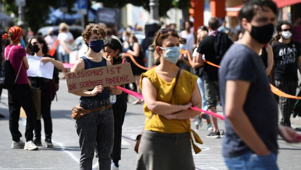 A person holds a banner reading Racism is the worst pandemic as participants of the so-called Indivisible demonstration form a human chain in support of the Black Lives Matter movement and to protest against the lockdown following the coronavirus disease (COVID-19) outbreak, in Berlin, Germany, June 14, 2020. A person holds a banner reading Racism is the worst pandemic as participants of the so-called Indivisible demonstration form a human chain in support of the Black Lives Matter movement and to protest against the lockdown following the coronavirus disease (COVID-19) outbreak, in Berlin, Germany, June 14, 2020. - Sputnik International