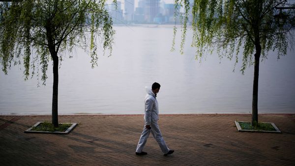 A man wearing protective gear walks by the Yangtze river in Wuhan, Hubei province, on April 4, 2020.  - Sputnik International