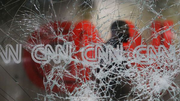 A security guard walks behind shattered glass at the CNN building at the CNN Center in the aftermath of a demonstration against police violence on Saturday, May 30, 2020, in Atlanta. - Sputnik International