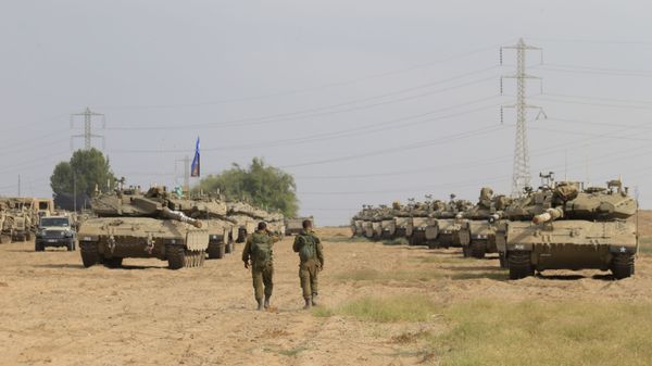 Israeli soldiers walk past tanks in a gathering point near Israel Gaza border, Friday, Oct. 19, 2018. - Sputnik International