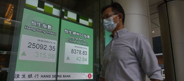 A man wearing a face mask walks past a bank electronic board showing the Hong Kong share index at Hong Kong Stock Exchange Tuesday, June 9, 2020. - Sputnik International