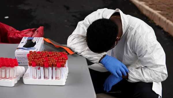 Overheated, a healthcare worker takes a break as people wait in their vehicles in long lines for the coronavirus disease (COVID-19) testing in Houston, Texas, US, July 7, 2020 - Sputnik International