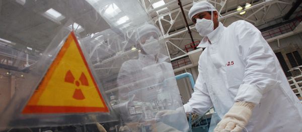 A man in protective gear standing near a hazard symbol - Sputnik International