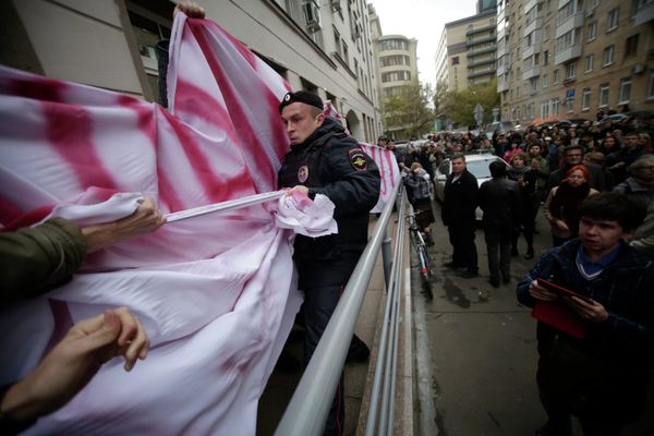 A police officer in a seeming tug-of-war with Mikhail Kosenko’s supporters outside a Moscow court, Oct. 8, 2013. - Sputnik International