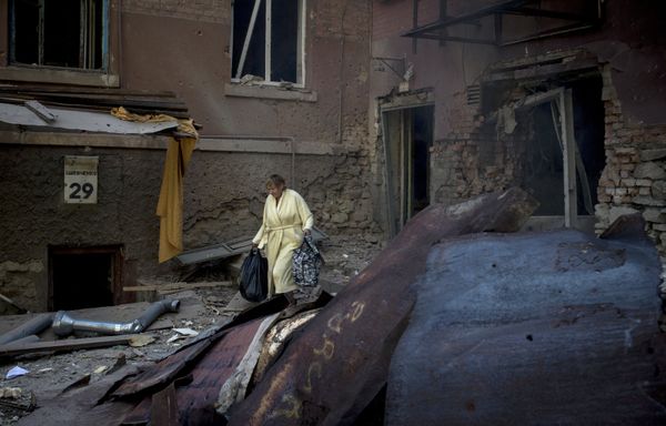 A woman is seen outside a residential building destroyed in an artillery attack by the Ukrainian army on Luhansk - Sputnik International