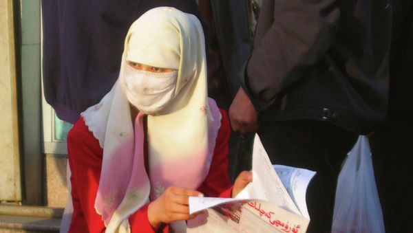 A Muslim woman reading a newspaper at a market place in the Xinjiang capital of Urumqi, the capital city of the Chinese restive Xinjiang region. - Sputnik International