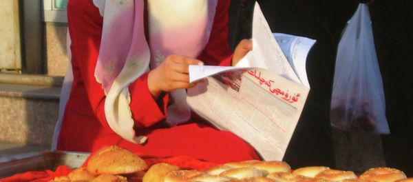 A Muslim woman reading a newspaper at a market place in the Xinjiang capital of Urumqi, the capital city of the Chinese restive Xinjiang region. - Sputnik International