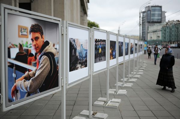 A resident of Moscow looking at the works of the Rossiya Segodnya photojournalist Andrei Stenin, killed in Ukraine, near the agency building in Moscow. - Sputnik International